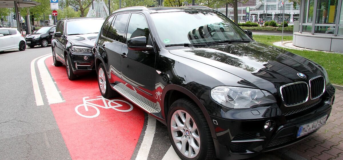 Schwarzer SUV parkt auf rot markiertem Radfahrstreifen